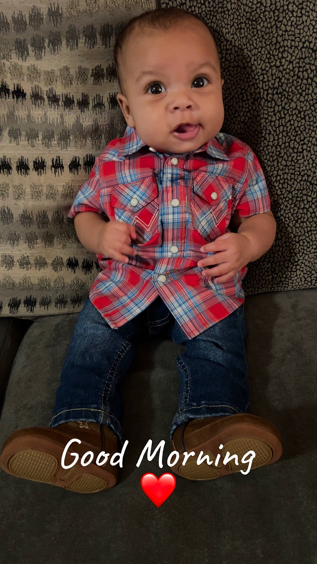 Jakobee is registered to the contest to win money with this photo: baby, brown_shoes, child, couch, cushion, cute, face, feet, hands, heart_emoji, indoor, jeans, morning, pattern, person, plaid_shirt, portrait, sitting, smiling, text_overlay