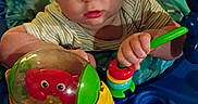 Ronnie joined the competition — help win amazing prizes! baby, child, toy, activity_center, indoor, carpet, couch, playing, colorful, hands, feet, person, infant, closeup, face, expression, furniture, striped_clothing, plastic_toy, development