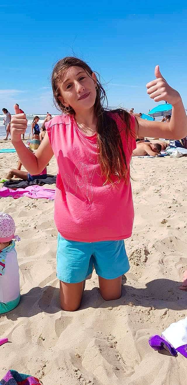 Chloé participe au concours pour gagner de l'argent avec cette photo : azure, beach, body_of_water, cool, finger, fun, gesture, happy, leisure, people_in_nature, people_on_beach, person, pink, sand, shorts, sky, sleeve, smile, summer, travel