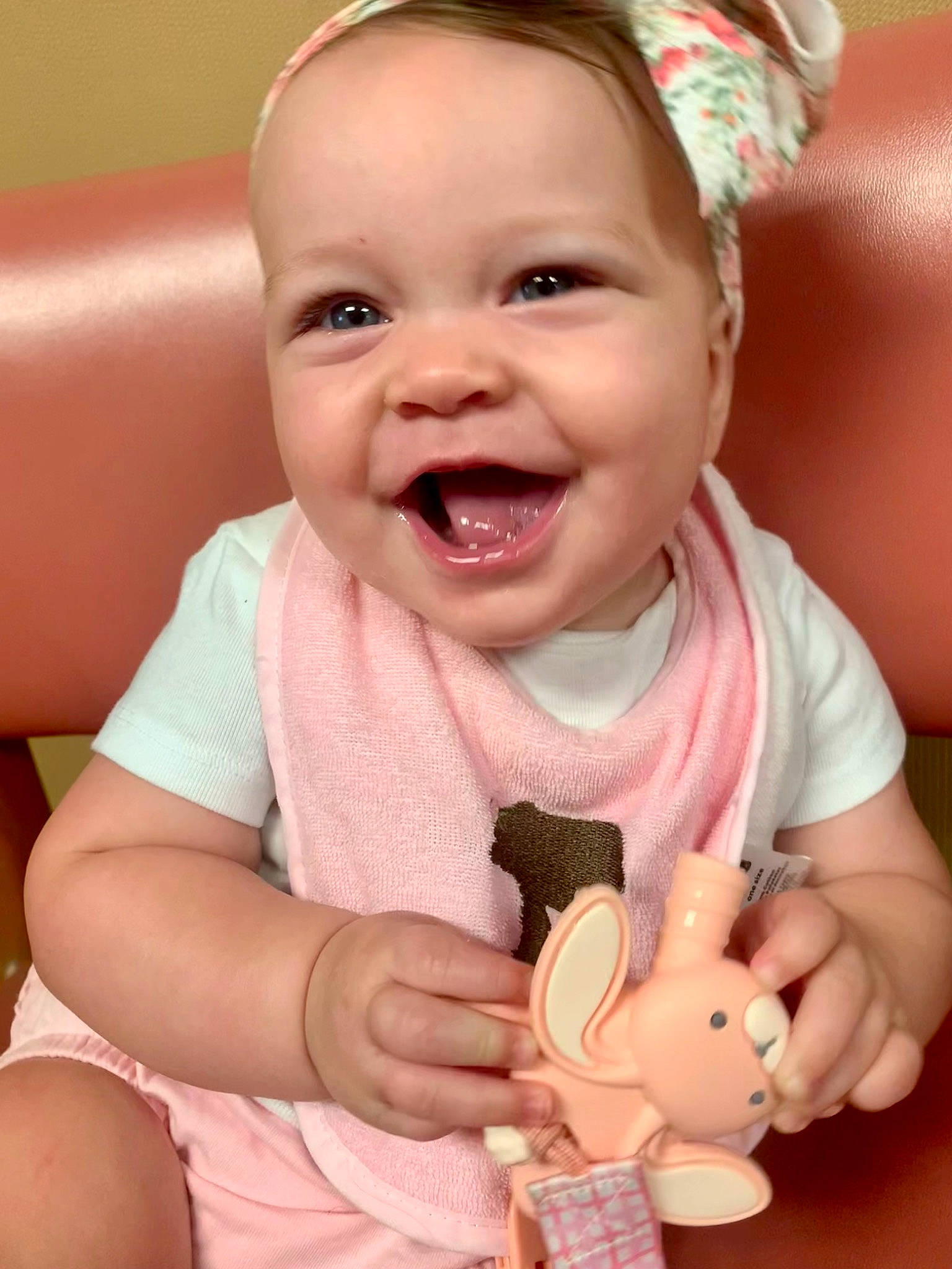 Dahlia is registered to the contest to win money with this photo: baby, baby_playing_with_toys, baby_toddler_clothing, cheek, facial_expression, finger, gesture, hand, happy, joy, mouth, nose, organ, person, pink, product, skin, smile, thumb, toddler