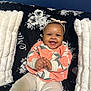 Milani joined the competition — help win amazing prizes! baby, smiling, child, headband, sweater, floral_pattern, couch, pillow, white, black, happy, indoor, portrait, seated, cute, infant, clothing, hands, face, comfort