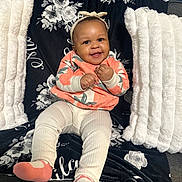 Milani is registered to the contest to win money with this photo: baby, child, smiling, sitting, headband, leggings, floral, blanket, pillow, couch, cozy, happy, cute, infant, apparel, pattern, indoor, comfort, portrait, person