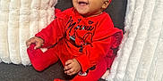 Milani joined the competition — help win amazing prizes! baby, child, smiling, red_clothing, headband, couch, pillows, indoor, happy, sitting, cute, portrait, infant, cozy, fashion, person, red_tights, red_socks, home, comfortable