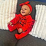 baby, child, smiling, red_clothing, headband, couch, pillows, indoor, happy, sitting, cute, portrait, infant, cozy, fashion, person, red_tights, red_socks, home, comfortable