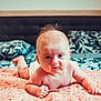 baby, infant, tummy_time, bed, pillow, blanket, skin, hair, face, curious, indoors, child, cute, young, lying_down, expression, soft_light, comfort, home, closeup