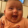 baby, smiling, infant, close_up, peach_outfit, bird_design, television, blurred_background, indoor, happy, cute, child, person, face, home, furniture, pacifier, apparel, portrait, joy