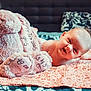 baby, infant, smiling, stuffed_animal, plush_toy, bed, blanket, pink, soft_toy, face, cute, child, lying_down, happy, indoors, home, comfort, toy, person, portrait
