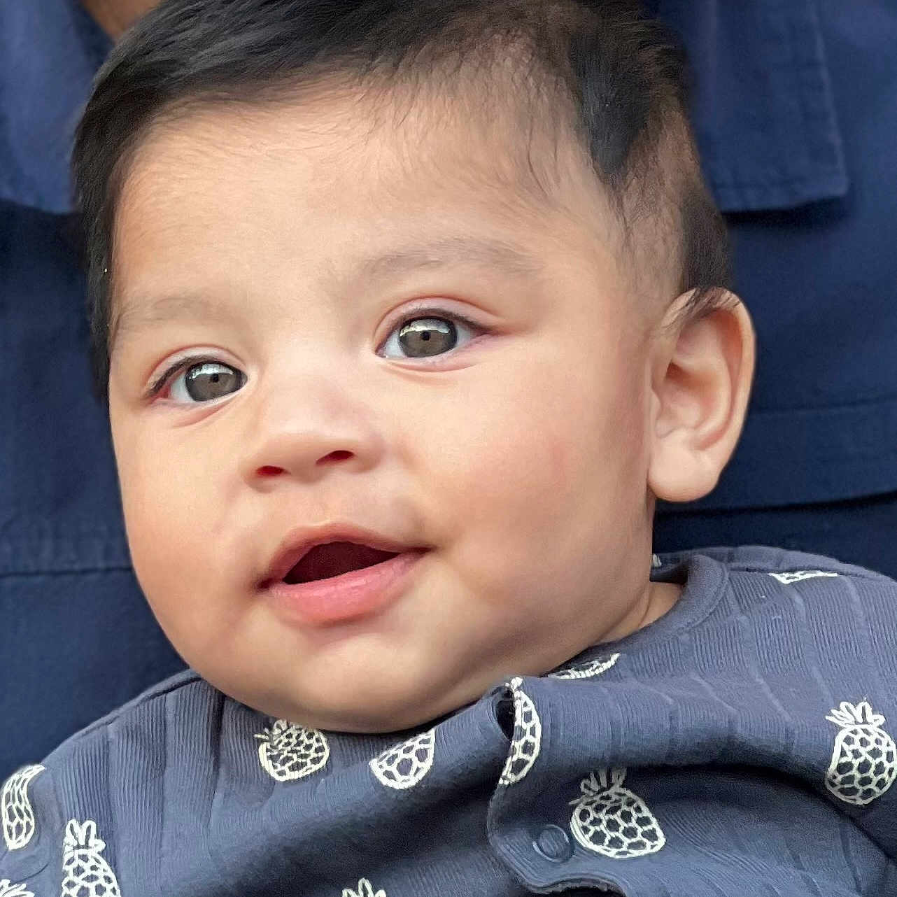 Daryl Jeremiah is registered to the contest to win money with this photo: baby, blue_outfit, child, closeup, clothing, cute, expression, eyes, face, happy, head, indoors, infant, mouth, person, pineapple_pattern, portrait, skin, soft_light, young