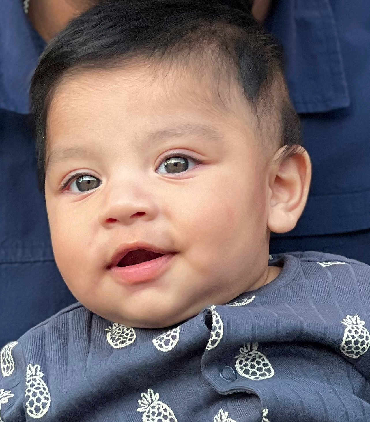 Daryl Jeremiah is registered to the contest to win money with this photo: baby, infant, face, eyes, mouth, clothing, pineapple_pattern, blue_outfit, closeup, portrait, child, cute, young, skin, expression, head, person, happy, indoors, soft_light