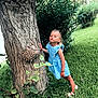 blue_dress, bushes, child, cute, daylight, girl, grass, greenery, leaf, nature, outdoor, person, playful, pose, pucker_lips, sandals, summer, tree, trunk, young