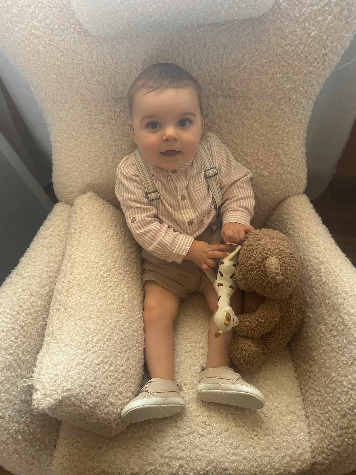 Victor participe au concours pour gagner de l'argent avec cette photo : baby, child, armchair, toy, teddy_bear, giraffe_toy, clothing, suspenders, shorts, shoes, striped_shirt, indoor, furniture, cozy, cute, smile, face, person, sitting, curious