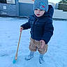 Aaron a rejoint le concours — aidez-le/la à gagner de superbes lots ! child, snow, winter_clothing, hat, jacket, broom, outdoor, snowy_ground, house, curious, boots, cold_weather, young_child, knitted_hat, playing, snow_boots, winter, standing, daylight, residential_area