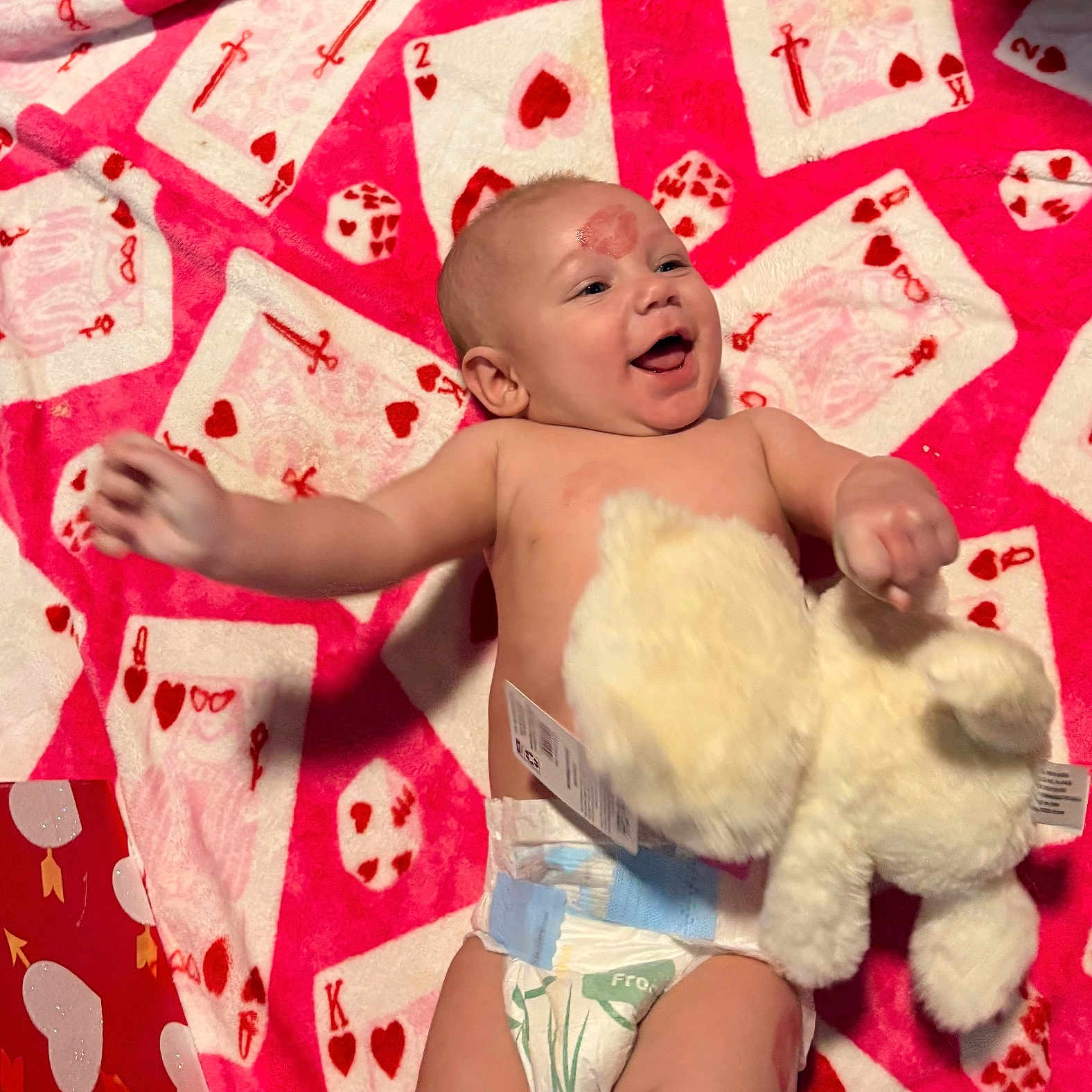 Javanhea joined the competition — help win amazing prizes! baby, blanket, child, cute, diaper, face, happy, head, indoors, infant, laughter, lying_down, pattern, playing_cards, red, skin, smiling, soft_toy, stuffed_animal, white