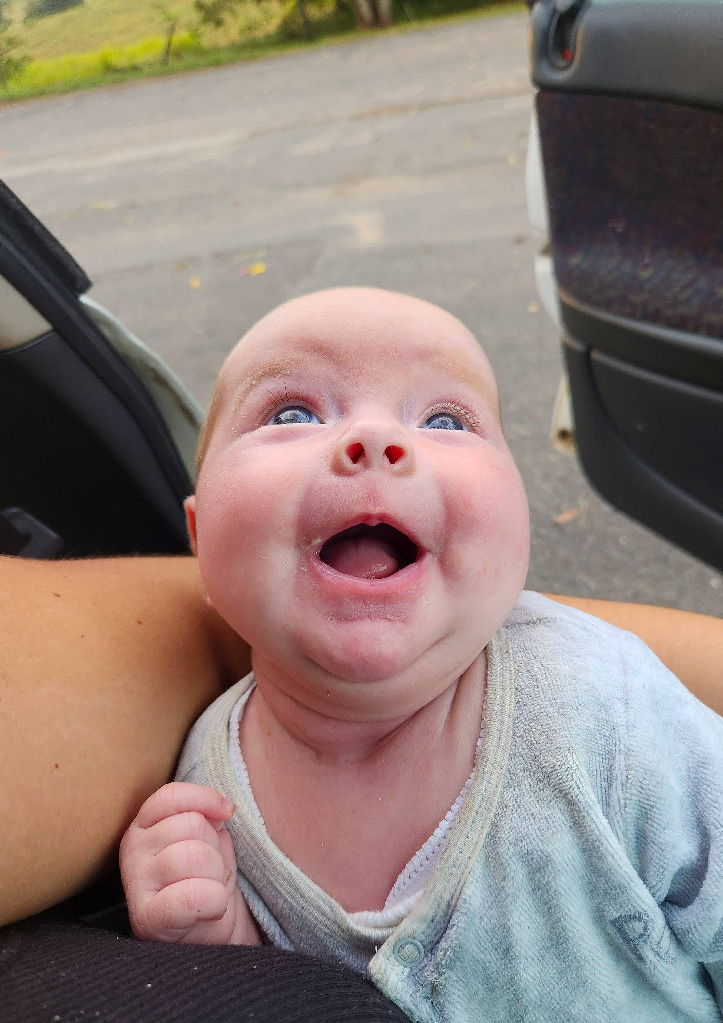 Evie is registered to the contest to win money with this photo: automotive_exterior, baby, eye, eyebrow, gesture, grass, happy, head, headwear, human_body, jaw, leisure, lip, motor_vehicle, nose, person, plant, smile, thumb, toddler