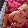 baby, child, smiling, tongue_out, crib, blanket, pink, toy, cute, happy, infant, playful, skin, person, sitting, indoors, face, expression, hand, young