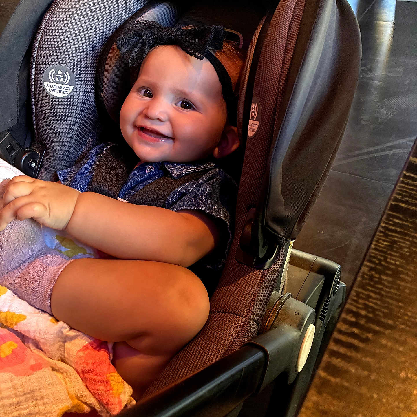 Emery is registered to the contest to win money with this photo: baby, child, car_seat, smiling, bow, blanket, indoor, person, cute, happy, toddler, clothing, sitting, face, headwear, infant, seat, young_child, portrait, comfort