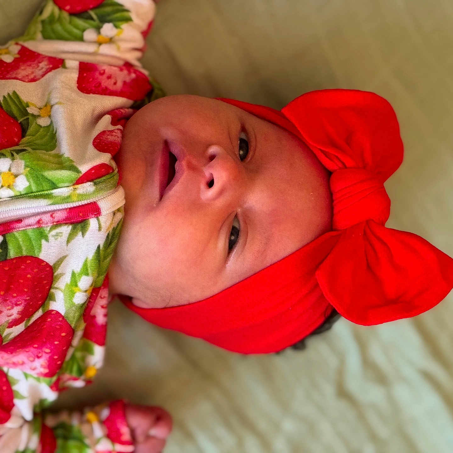 Haysley joined the competition — help win amazing prizes! baby, child, clothing, colorful, cute, expression, face, fashion, headband, indoors, infant, lying_down, person, portrait, red_bow, skin, sleepwear, soft_surface, strawberry_pattern, young