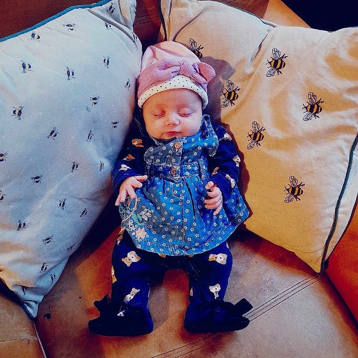 Blake-Blu is registered to the contest to win money with this photo: baby, bonnet, cap, clothing, couch, cushion, dress, face, furniture, glove, hat, head, homedecor, newborn, pants, person, photography, pillow, portrait, sleeping