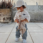 Juliann a rejoint le concours — aidez-le/la à gagner de superbes lots ! toddler, child, pacifier, plush_toy, cap, striped_pants, white_shoes, outdoor, plant, potted_plant, wall, tile_floor, cute, standing, young_child, clothing, casual, innocence, daylight, portrait