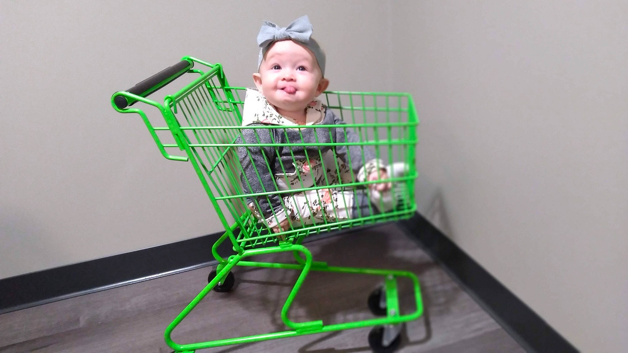 Remi is registered to the contest to win money with this photo: baby, baby_products, baby_safety, cart, child, cleanliness, flooring, fun, magenta, person, plastic, play, retail, shopping_cart, sleeve, smile, toddler, toy, vehicle