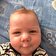 Mélicio participe au concours pour gagner de l'argent avec cette photo : baby, infant, face, smile, hair, onesie, striped_clothing, blue_blanket, closeup, cheeks, skin, eyes, button, pattern, fabric, cute, lying_down, child, portrait, indoors