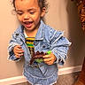 child, toddler, denim_jacket, denim_skirt, toy_dinosaur, curly_hair, happy, smiling, indoor, carpet, wall, footwear, boot, person, clothing, play, cute, earring, standing, colorful