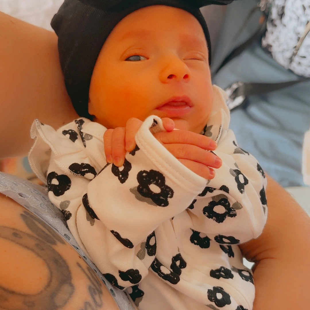 Anlee joined the competition — help win amazing prizes! arm, baby, baby_fashion, black_headwrap, close_up, cute, floral_outfit, hand, holding, indoor, infant, newborn, newborn_clothing, person, portrait, skin, sleepy, soft_light, tattoo, winking