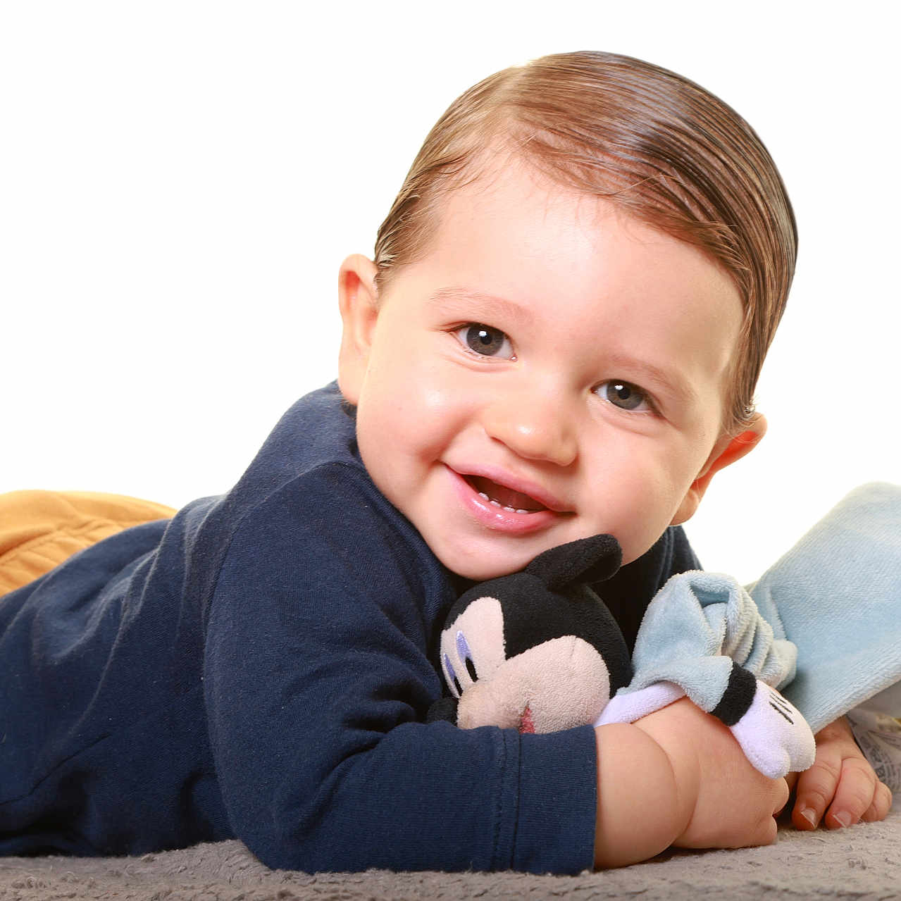 Vychenzo participe au concours pour gagner de l'argent avec cette photo : baby, blue_sweater, brown_pants, child, closeup, cuddly, cute, face, happy, indoor, infant, lying_down, mickey_mouse, person, playful, plush, portrait, smiling, soft_rug, toy