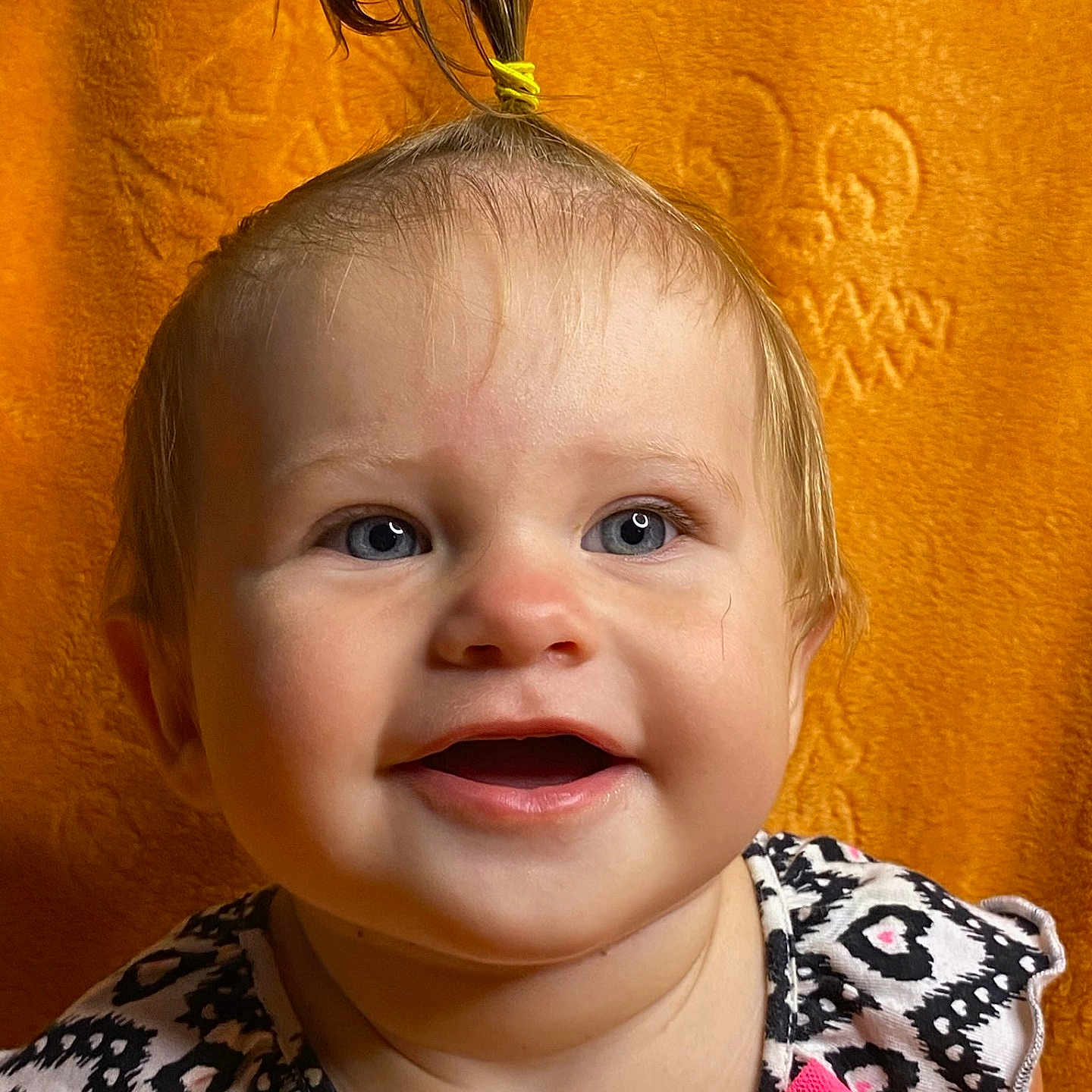 Katharina is registered to the contest to win money with this photo: baby, blue_eyes, child, close_up, cute, expression, face, hair_tie, happy, indoor, infant, orange_background, patterned_dress, person, pink_bow, ponytail, portrait, smile, toddler, young_child