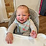 Canelo is registered to the contest to win money with this photo: baby, high_chair, bib, smiling, indoor, child, wooden_floor, brick_wall, happy, person, table, feeding_time, cute, infant, clothing, face, hand, seat, domestic, home