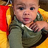 toddler, baby, child, face, blue_eyes, green_sweater, baby_seat, yellow, red, hand, indoor, curious, expression, person, young_child, candid, portrait, furniture, household, closeup