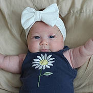 Kalinah joined the competition — help win amazing prizes! baby, baby_girl, beige_background, blue_eyes, bow, chubby_cheeks, closeup, clothing, cushion, cute, daisy, headband, indoors, infant, navy_outfit, person, portrait, raised_arms, smiling, soft_light