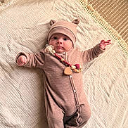 Ezekiel a rejoint le concours — aidez-le/la à gagner de superbes lots ! baby, infant, onesie, hat, pacifier, blanket, carpet, indoor, cute, child, lying_down, soft_texture, beige, warm_colors, patterned_rug, cozy, portrait, small_hands, wide_eyes, headwear