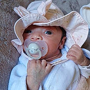 Aaliyah participe au concours pour gagner de l'argent avec cette photo : baby, newborn, infant, pacifier, hat, pink_hat, blanket, hand, eyes, face, close_up, portrait, cozy, soft_texture, clothing, lying_down, cute, bed, indoors, skin