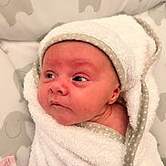 Riley is registered to the contest to win money with this photo: baby, infant, towel, hooded_towel, wrapped, face, skin, eyes, expression, elephant_pattern, background, soft_texture, newborn, cute, child, indoors, portrait, cozy, blanket, resting