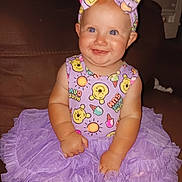 Jasmine joined the competition — help win amazing prizes! baby, tutu, purple, headband, smiling, sitting, couch, indoor, child, happy, clothing, cute, portrait, infant, person, face, playful, cartoon_print, headwear, bright