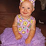 baby, tutu, purple, headband, smiling, sitting, couch, indoor, child, happy, clothing, cute, portrait, infant, person, face, playful, cartoon_print, headwear, bright
