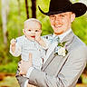 baby, boutonniere, bow_tie, child, cowboy_hat, footwear, forest, formal_wear, greenery, happy, holding, light, man, nature, outdoor, person, portrait, smile, suit, vest