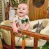 Gunner joined the competition — help win amazing prizes! baby, bunny, carrot, chair, child, cute, decorative, face, grass, green_bow_tie, happy, indoor, person, plush, rabbit, sitting, smiling, wooden_decor, wooden_fence, wreath