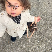 Melia participe au concours pour gagner de l'argent avec cette photo : child, toddler, curly_hair, trench_coat, floral_top, handbag, purse, looking_up, blue_eyes, serious_expression, outdoor, sidewalk, gravel, boots, fashion, portrait, single_person, ground_texture, accessory, street_style