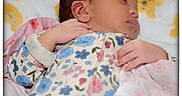Nasya is registered to the contest to win money with this photo: baby, sleeping, infant, pajamas, floral_pattern, blanket, bed, soft_toys, teddy_bear_pattern, peaceful, closeup, face, hand, cute, child, resting, indoors, portrait, newborn, cozy