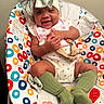 baby, child, infant, smiling, headband, bow, green_socks, baby_seat, colorful, pattern, happy, clapping, cute, indoors, closeup, person, toddler, playful, apparel, seat