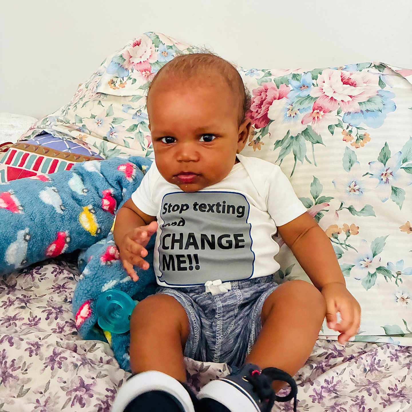 Jasia joined the competition — help win amazing prizes! baby, infant, child, onesie, clothing, bed, pillow, floral_pattern, plush_toy, pacifier, sitting, footwear, socks, expression, indoor, cute, person, text, humor, portrait