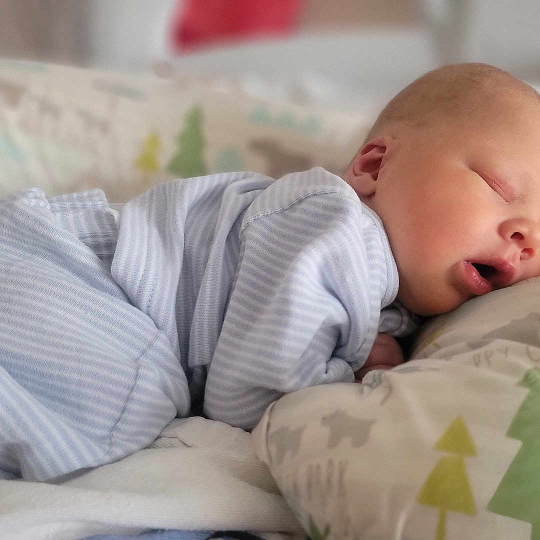 Graham is registered to the contest to win money with this photo: baby, bed, blanket, child, comfort, cozy, cute, face, head, indoors, infant, newborn, pajamas, peaceful, pillow, rest, skin, sleeping, soft_fabric, striped_clothing