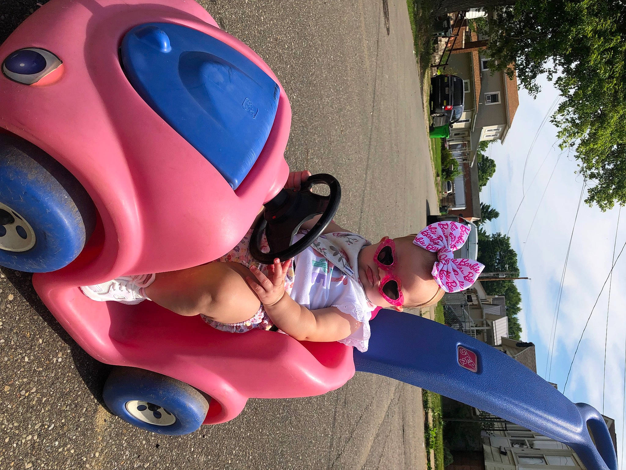 Kynlee is registered to the contest to win money with this photo: automotive_design, automotive_tire, fender, fun, helmet, leisure, magenta, person, photograph, pink, plant, public_space, purple, red, riding_toy, sky, tire, tree, vehicle, wheel