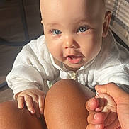 Jalil a rejoint le concours — aidez-le/la à gagner de superbes lots ! baby, child, blue_eyes, hand, fingers, skin, legs, knees, white_clothing, indoor, sunlight, shadow, person, holding_hand, cute, infant, closeup, expression, family, warm_light