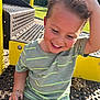 child, boy, smiling, playground, outdoor, greenery, sunlight, short_sleeve_shirt, toddler, happy, wood_chips, metal_bench, yellow, casual_clothing, playing, summer, fun, daylight, park, closeup