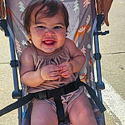 Emery joined the competition — help win amazing prizes! toddler, child, smiling, stroller, outdoor, sunlight, playful, happy, cute, infant, clothing, seatbelt, fabric, animal_print, legs, hands, person, face, baby, seat