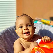 Milan participe au concours pour gagner de l'argent avec cette photo : baby, infant, child, smiling, happy, bare_shoulders, orange_inflatable, float, towel, indoor, sunlight, face, hands, skin, portrait, cute, young, playful, bright, warm