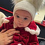Paisley joined the competition — help win amazing prizes! baby, child, hat, pom_poms, red_coat, white_trim, hand, ring, indoor, portrait, cute, warm_clothing, winter_wear, festive, curious, seated, soft_light, face, person, expression